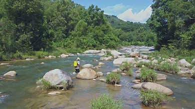 Drone Approaches Man with Fishing Rod Walking among Rapids