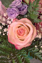 A bucket of flowers with pink and violet roses
