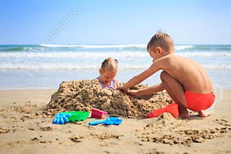 Little Girl Boy Sit near Heap Play at Wave Surf on Beach