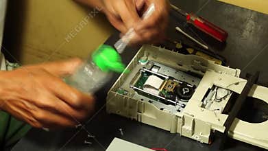 Technician moistens cotton swab with alcohol to clean DVD laser head