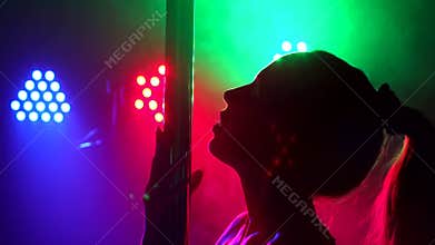 Silhouette of a girl performing dance on a pole.