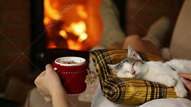 Woman relaxing on couch with a warm drink and her cat