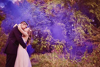 Bride and Groom kissing in forest with purple smoke