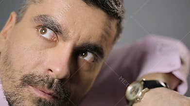 Crazy man listening to watch ticking, moving eyes from side to side, time flying