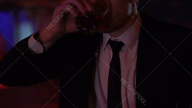 Businessman drinking alone in bar, pondering over business solutions, closeup