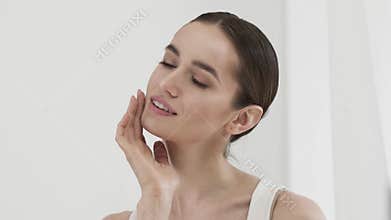 Beauty Care. Attractive Smiling Woman Caressing Face Skin