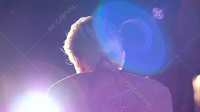 Music concert, beautiful young singer on stage with microphone performs song in lighting