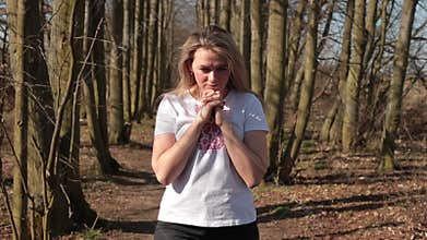 The woman is moving in forest road. She holds her hands chest, thinks herself