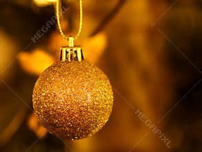 Golden glittering Christmas bauble close-up by blurred background