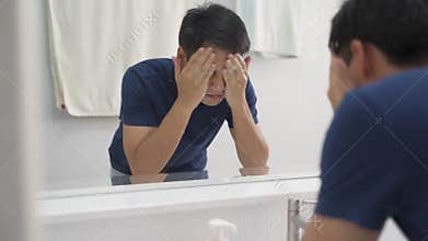 Asian man washing face with pure water and facial foam for refreshment from tired. male splashing water into face in clean white b