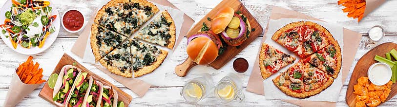 Healthy plant based fast food table scene. Overhead view on a white wood banner background.