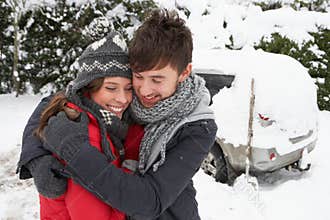Young couple in snow with car