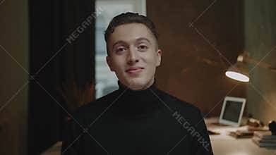 Cheerful guy looks straight and smiles sitting at conference
