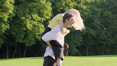 Couple of teenagers guy and girl 16, 17 years old are having fun together in park on green lawn