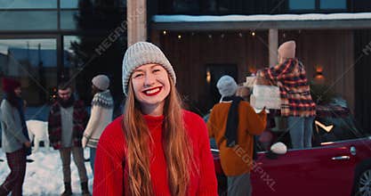 Portrait of young beautiful happy blonde woman in red sweater smile at camera at fun Christmas friends party slow motion