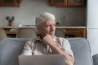 Pensive stressed mature 70s man holding laptop computer
