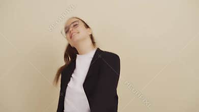 Beautiful young woman dances on beige background.