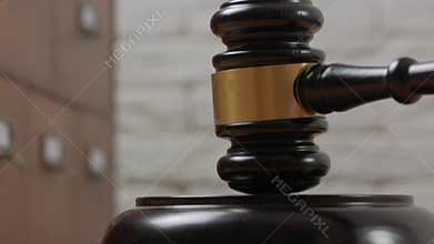 Close-up of a judge hitting a block with a hammer in a courtroom.