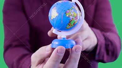 Close-up shot of man`s hands who is a travel agent keeping a globe,demonstrating a big variety of traveler`s locations on the