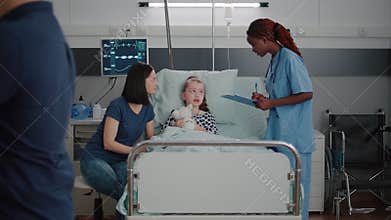Sick child wearing oxygen nasal tube resting in bed in hospital ward