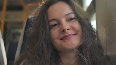 Woman enjoying a train journey while smiling at the changing scenery