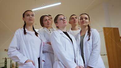 Group of young medical students standing together, looking ahead with confidence in white lab coats. Concept of teamwork