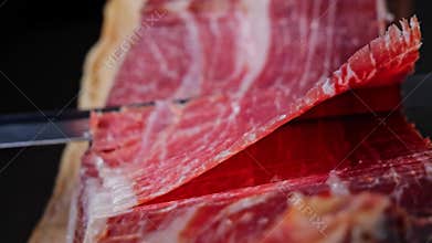 Cutting slicing a traditional Iberico Spanish ham, jamon. Whole leg. Close up