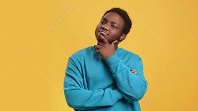 Pensive African man thinking making difficult decision solving problem posing isolated on orange