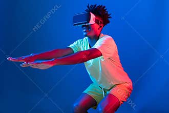 African American wearing VR exercising body weight squat neon wall. Contrivance.