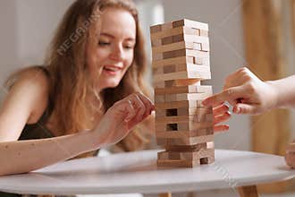 two women playing Jenga board game at home, excitement and relaxation, mind development concept,