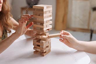 two women playing Jenga board game at home, excitement and relaxation, mind development concept,