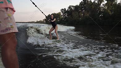 A girl holding onto a rope rides a wakeboard.