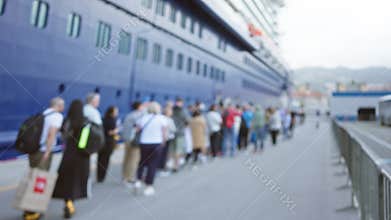 Crowd standing in blurred line outdoors by docked cruise ship at port waiting to board under bright sky in soft focus