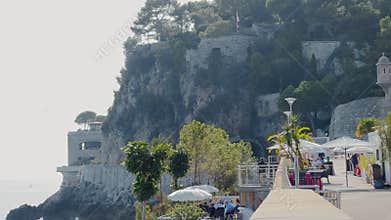 Monaco, Monte Carlo, 25 October 2022: Cafe embankment on the pier in the port of Monaco, a mountain in the background at