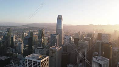 Aerial view of a city skyline at sunset with modern skyscrapers and warm sunlight bathing the buildings