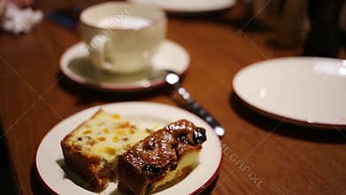 Pieces of cake on plate and white cup of tea on