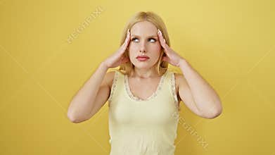 Depressed young blonde woman wearing a sleeveless tshirt, hand over her aching head, suffering a stressed-induced migraine. an