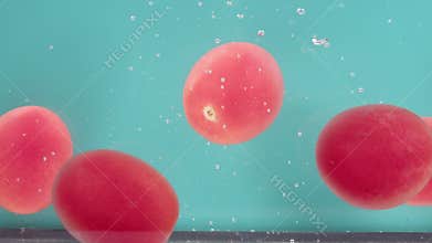 The several vegetables of ripe red tomatoes on a turquoise background immerse in water, form bubbles, sink and settle to