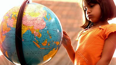 Little girl looking at globe in classroom