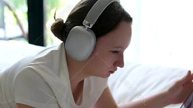 headphones, bed, girl, tablet young girl puts on headphones, a tablet, and lies on her stomach on a bed, learning online