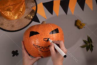 Drawing Scary Face on Pumpkin for Halloween Decoration at Home