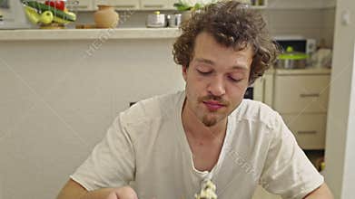 A young man enjoys his delicious meal with audible sounds in a cozy kitchen setting at home