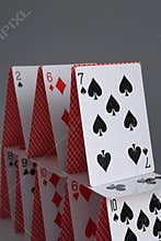 House of playing cards on grey background, closeup