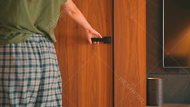 Smart home system, lights turn on by human motion sensor, person gripping close-up of black door handle, hand closing