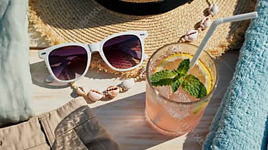 Summer vacation flat lay arrangement featuring clothing, beach accessories and a refreshing drink on a wooden background.