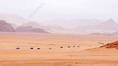 Convoy of off road vehicles crossing Wadi rum desert with dunes mountains remote transport film production logistics concept