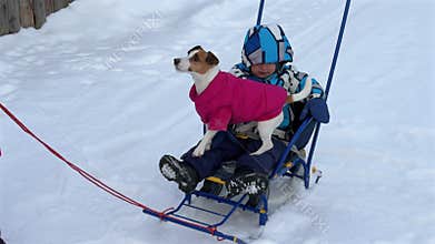 A woman carries her son and dog on a sled.