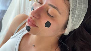 Young woman getting carbon laser facial at beauty clinic. Professional skincare