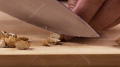 female hands chopping almond nuts on board