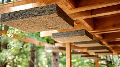 Medium shot of natural wool insulation panels being installed between wooden beams in a cozy home highlighting